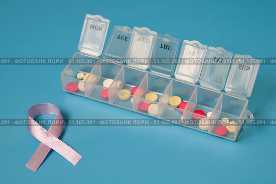 Daily pill organizer filled with pills and lavender awareness ribbon symbolizing general cancer awareness. Стоковое фото, фотограф Дмитрий Цветков / Фотобанк Лори