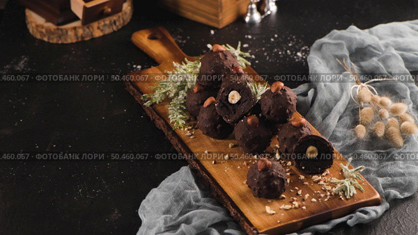 Dark chocolate truffles with hazelnuts over wooden cutting board. Стоковое фото, агентство Ingram Publishing / Фотобанк Лори