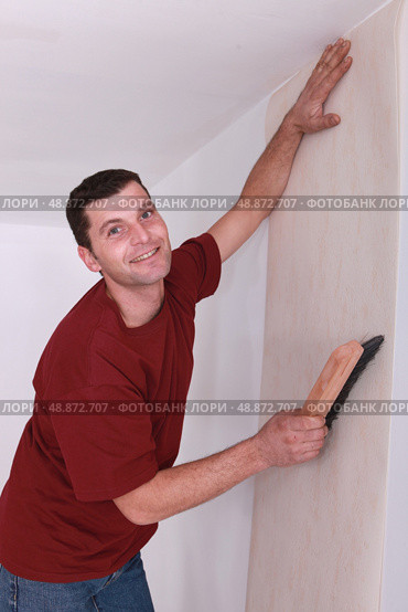Decorator smoothing wallpaper. Стоковое фото, агентство Ingram Publishing / Фотобанк Лори