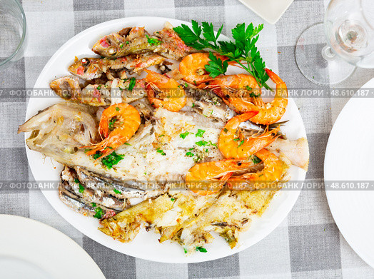 Deep-fried fish carcasses are served on plate - assorted Atlantic sea fish and shrimp. Стоковое фото, фотограф Яков Филимонов / Фотобанк Лори