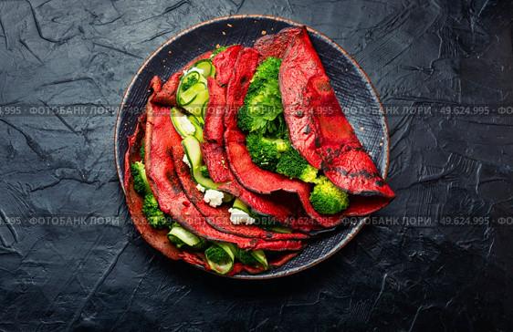 Delicious beetroot pancakes with broccoli and cucumber on a slate background. Vegetarian food. Pancakes from beetroot, vegetable flapjack. Стоковое фото, агентство Ingram Publishing / Фотобанк Лори