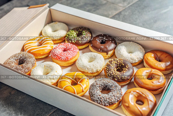 Delicious dessert. A sick box of different donuts with colorful sprinkles on the table. Confectionery products. Стоковое AI-изображение, AI-художник Photojuli / Фотобанк Лори