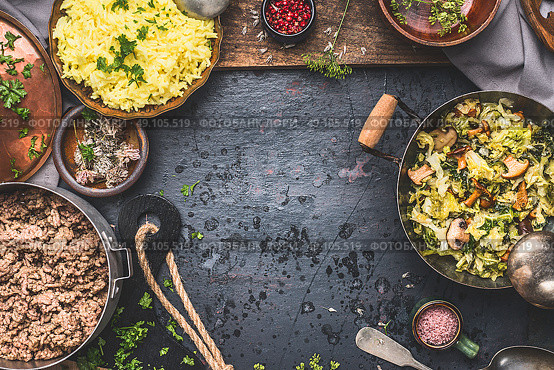 Delicious dish with  stewed chopped cabbage and mushrooms, yellow rice and mincemeat on dark background , top view. Rustic food cooking. Стоковое фото, агентство Ingram Publishing / Фотобанк Лори