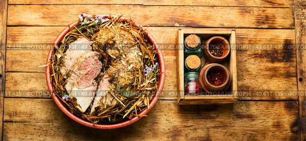 Delicious meat roasted in fresh hay. Baked pork meat in spicy herbs.. Roast pork in hay with herbs,top view. Стоковое фото, агентство Ingram Publishing / Фотобанк Лори