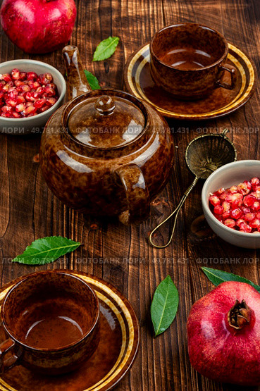 Delicious red tea and pomegranate on table in the teakettle.. Tea With Pomegranate Seeds. Стоковое фото, агентство Ingram Publishing / Фотобанк Лори