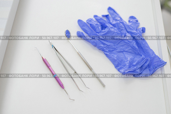 Dentist's table with sterile tools on a white background top view. A mirror, tweezers, a probe and gloves are on the doctor table. Oral hygiene, caries prevention, examination. Стоковое фото, фотограф Михаил Решетников / Фотобанк Лори