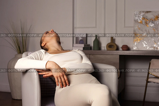 Depressed young lady with emotional stress suffering from mental health sitting on armchair in living room. Distress lone woman lying down at home. Healthcare and medical concept. Copy ad text space. Стоковое фото, фотограф Aleksandr Golubev / Фотобанк Лори