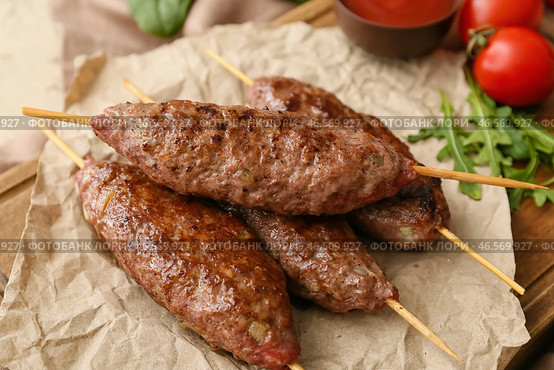 Деревянная доска с шампурами и вкусным люля-кебабом на столе, крупным планом. Стоковое фото, фотограф Pixel_shot / Фотобанк Лори