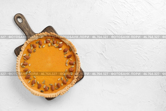Деревянная доска с вкусным тыквенным пирогом с миндалем и семечками на белом фоне. Стоковое фото, фотограф Pixel_shot / Фотобанк Лори