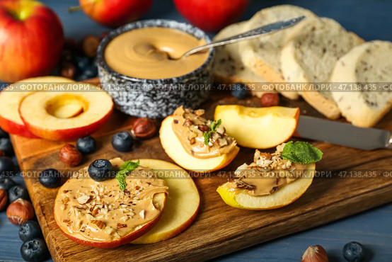 Деревянная доска с вкусными яблочными кружочками и дольками с ореховым маслом, крупным планом. Стоковое фото, фотограф Pixel_shot / Фотобанк Лори