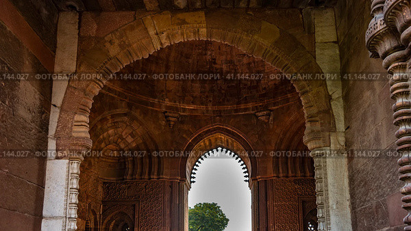 Details of the architecture of the ancient temple complex Qutub Minar. The arches of the sandstone building are decorated with carvings. The blue sky is visible in the opening. India. Delhi (2022 год). Стоковое фото, фотограф Вера Ивановна Кубарева / Фотобанк Лори