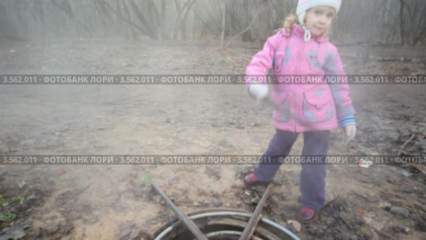 Девочка с палкой стоит возле канализационного люка. Стоковое видео, видеограф Losevsky Pavel / Фотобанк Лори