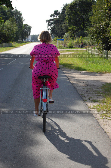 Девушка на велосипеде едет по сельской дороге (2009 год). Редакционное фото, фотограф Федор Болба / Фотобанк Лори