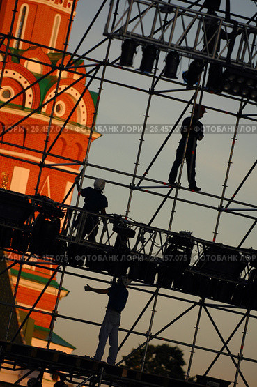 Diagonal view on workers on stage construction levels at Moscow Red Square in front of Vasiliy Blazhenniy Cathedral. Workers shadow figures on staging construction. Pop music stage under construction (2005 год). Редакционное фото, фотограф Mikhail Leonov / Фотобанк Лори