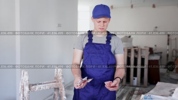 Discontented teenager boy holding bunch of money he earned by working on his first job in construction site. Стоковое видео, видеограф Яков Филимонов / Фотобанк Лори