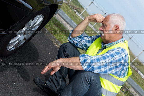 discouraged retired man unable to change car tyre. Стоковое фото, агентство Ingram Publishing / Фотобанк Лори