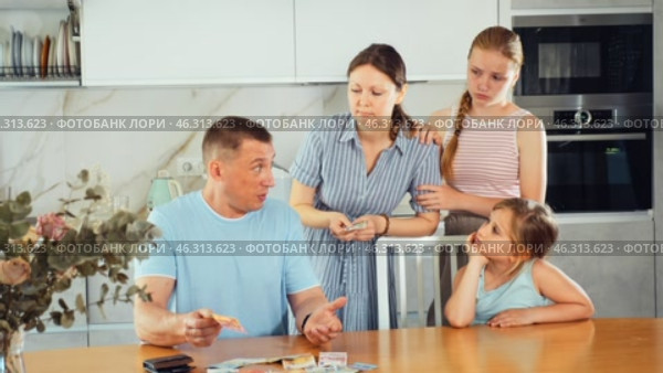 Dissatisfied husband and father give out pocket money to wife and children in home kitchen. Стоковое видео, видеограф Яков Филимонов / Фотобанк Лори