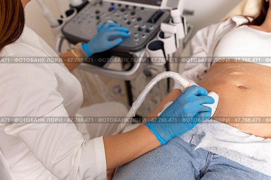 Doctor hands with ultrasonic during ultrasound medicine examination of pregnant patient. Maternity, pregnancy, fertility concept. Future mom checking on the embryo. High quality photo. Top view. Стоковое фото, фотограф Ирина Михайличенко / Фотобанк Лори