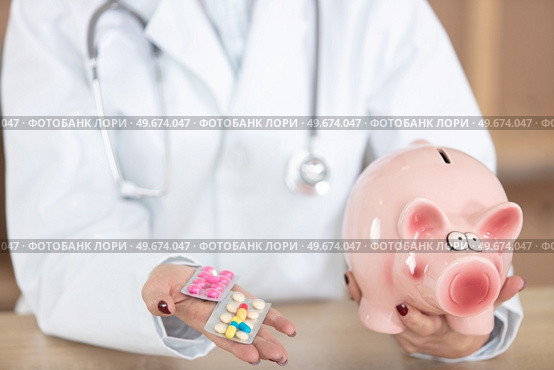 doctor holding piggybank and blisters of tablets. Стоковое фото, агентство Ingram Publishing / Фотобанк Лори