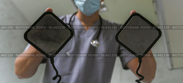 doctor with medical mask using defibrillator. Стоковое фото, агентство Ingram Publishing / Фотобанк Лори