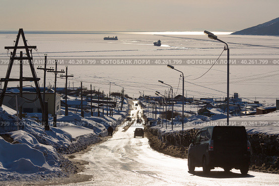 Дорога к морю. Машины едут по улице в сторону морской бухты. Бухта покрыта льдом. Среди льдин корабли. Конец марта на Крайнем Севере. Бухта Нагаева, Магадан, Сибирь, Дальний Восток России. Стоковое фото, фотограф Андрей Степанов / Фотобанк Лори