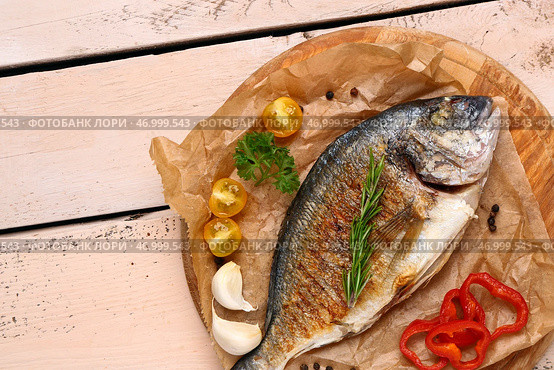 Доска с вкусной жареной рыбой дорадо на светлом деревянном фоне. Стоковое фото, фотограф Pixel_shot / Фотобанк Лори