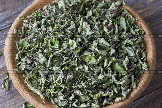 Dried oregano leaves in a wooden bowl on a wooden table, top view, close-up. Стоковое фото, фотограф Ольга Лепёшкина / Фотобанк Лори
