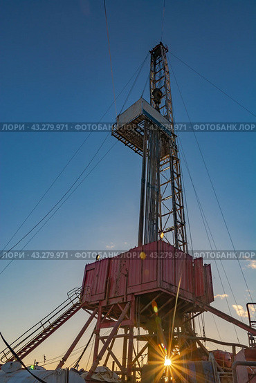 Drilling rig for deep drilling for oil and gas with a sunbeam at the base. The image of bursting energy of the subsoil. Many drill pipes installed vertically. Стоковое фото, фотограф Владимир Ендовицкий / Фотобанк Лори