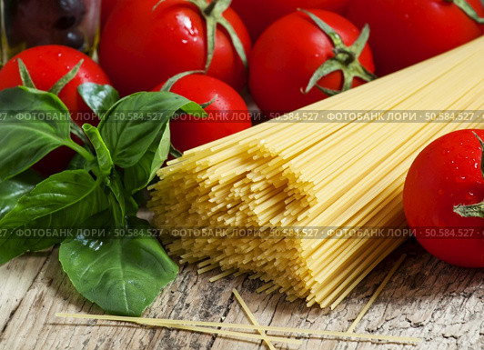 Dry Italian pasta Capellini with tomato and basil on old wooden table, selective focus. Стоковое фото, агентство Ingram Publishing / Фотобанк Лори
