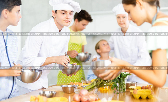 During cooking lesson, male cook tells children about culinary rules, woman assistant helps child. Стоковое фото, фотограф Яков Филимонов / Фотобанк Лори