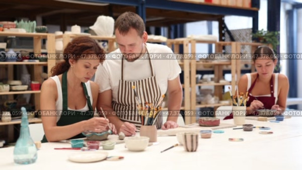 During master class, student paints clay vessel under guidance of male teacher. Стоковое видео, видеограф Яков Филимонов / Фотобанк Лори