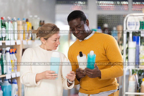 During shopping, African male customer with European wife advised and choose shampoo or shower gel. Стоковое фото, фотограф Яков Филимонов / Фотобанк Лори