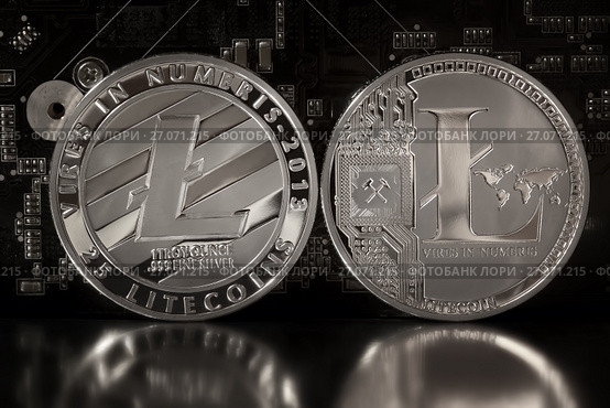 Две стороны монеты Litecoin (форк Биткоина) - децентрализованная криптовалюта с открытым кодом на фоне платы с микросхемами. Стоковое фото, фотограф Николай Винокуров / Фотобанк Лори