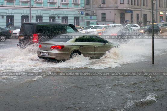 Движение транспорта по воде во время сильного дождя. Новый Арбат, Москва (2018 год). Редакционное фото, фотограф Pukhov K / Фотобанк Лори