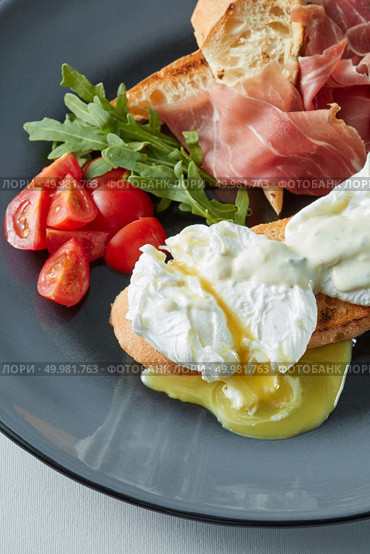 Eggs Benedict with ham and tomato on toast with cheese. Eggs Benedict with bacon, toast and salad. Стоковое фото, агентство Ingram Publishing / Фотобанк Лори