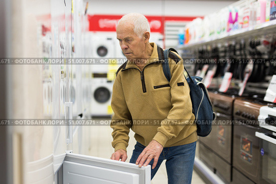 elderly man choosing refrigerator in showroom of electrical appliance store. Стоковое фото, фотограф Татьяна Яцевич / Фотобанк Лори
