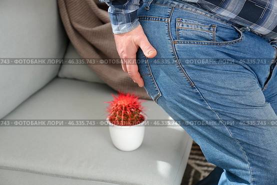 Elderly man near sofa with cactus at home. Hemorrhoids concept. Стоковое фото, фотограф Pixel_shot / Фотобанк Лори
