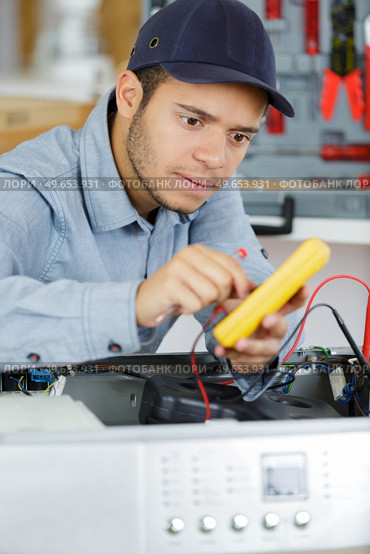 electrician is repairing a clothes washer with gripper. Стоковое фото, агентство Ingram Publishing / Фотобанк Лори