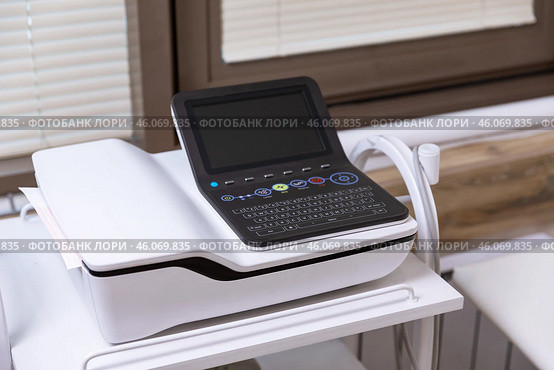 Electrocardiogram equipment for making cardiogram test of patient who is attached with vacuum sensors to the machine near coach in medical office room. Healthcare concept. Стоковое фото, фотограф Ирина Михайличенко / Фотобанк Лори