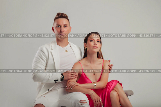 Elegant couple in modern attire posing in studio setting, showcase connection through subtle touches and poised expressions, enhances their elegance. Style fashion trendy concept. Copy ad text space. Стоковое фото, фотограф Aleksandr Golubev / Фотобанк Лори