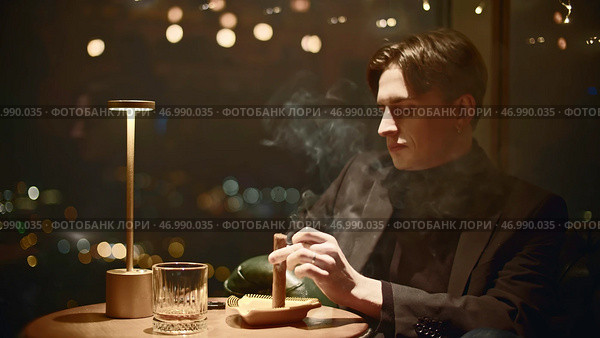 Elegant man in suit smokes cigar in restaurant. Стоковое фото, фотограф David Kashakhi / Фотобанк Лори