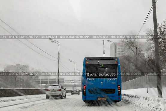 Электробус следует по маршруту №38 по Сущевской улице в городе Москве. Январская непогода, снегопад. Вид через мокрое лобовое стекло автомобиля (2021 год). Редакционное фото, фотограф Наталья Николаева / Фотобанк Лори