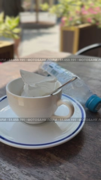 Empty coffee cup on saucer with spoon and plastic bottle on wooden table outdoors. Стоковое видео, видеограф Анастасия Золотницкая / Фотобанк Лори