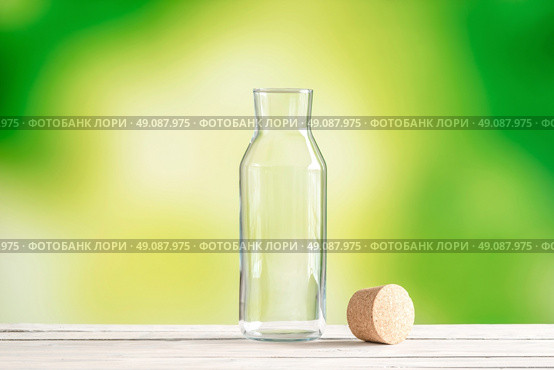 Empty glass bottle with a cork on green background. Стоковое фото, агентство Ingram Publishing / Фотобанк Лори