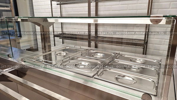 Empty stainless steel food serving trays in cafeteria with glass partition. Стоковое фото, фотограф Zakharova Natasha / Фотобанк Лори