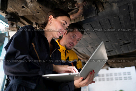 Engineers and auto repair technicians must use technology to detect faults in the operation of the engine of customer cars brought to repair in the garage. Стоковое фото, агентство Ingram Publishing / Фотобанк Лори