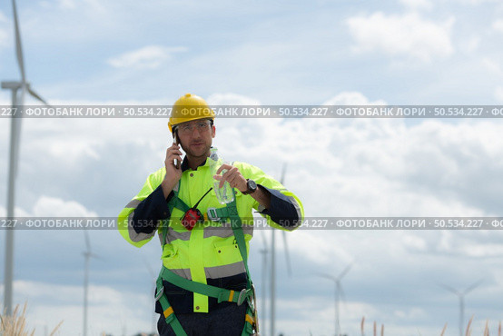 Engineers are using a smartphone to check the wind turbine in the field, The concept of natural energy from wind. Стоковое фото, агентство Ingram Publishing / Фотобанк Лори