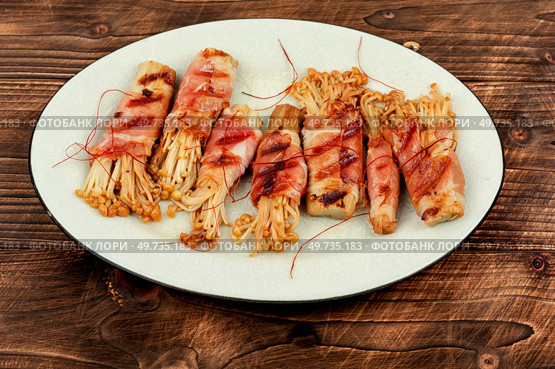 Enoki mushroom appetizer fried in bacon on wooden table. Asian cuisine. Enoki mushroom appetizer fried in bacon. Стоковое фото, агентство Ingram Publishing / Фотобанк Лори