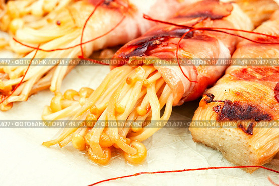 Enoki mushroom roasted in bacon on plate. Bacon wrapped mushroom. Asian food. Close up.. Enoki mushrooms rolls. Стоковое фото, агентство Ingram Publishing / Фотобанк Лори