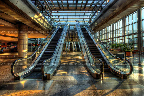 Escalators leading to sunlight filled modern building. Стоковое AI-изображение, AI-художник Иван Рябоконь / Фотобанк Лори